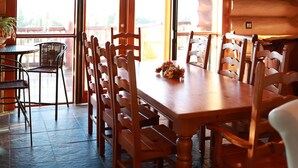 Un comedor con mesa y sillas de madera, ventanas amplias y un ventilador de techo.