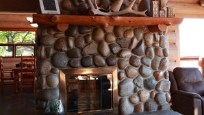 Una chimenea de piedra con una figurita de venado, un estante de madera con un cuadro y una copa de vino.
