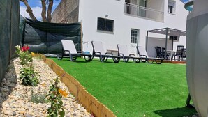 A white building with a balcony, outdoor seating area with chairs, and a green artificial lawn. - With a view of Serra de Aire e Candeeiros, with a calm location (Petfriendly). (Cruz da Légua)