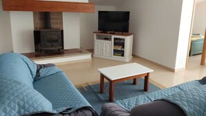 A living room with a fireplace, a television on a cabinet, and a sofa. - With a view of Serra de Aire e Candeeiros, with a calm location (Petfriendly). (Cruz da Légua)