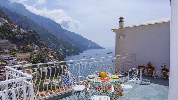 Una terraza con una mesa lista para comer, con vistas a un pueblo costero y al mar.