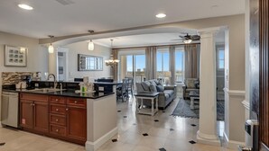 A spacious living area with a large island, a dining area, and a view of the outdoors.