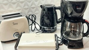 Uma bancada de cozinha com uma torradeira, uma cafeteira, uma chaleira e um cozido de arroz.