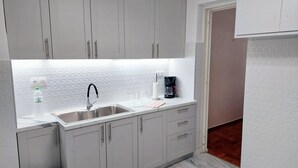 Uma cozinha moderna com uma pia de aço inoxidável, uma cafeteira e uma garrafa de água.