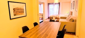 Ein Hotelzimmer mit einem Holztisch, einer Couch, einem Bett und einem gerahmten Bild an der Wand.