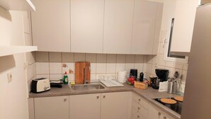 A compact kitchen with white cabinets, a stainless steel sink, a toaster, a coffee maker, and a kettle. - Big Apartment in Acropolis Museum (Athens)