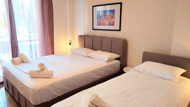 A hotel room with two beds, each with white linens and towels, a headboard, and a framed picture on the wall. - Big Apartment in Acropolis Museum (Athens)