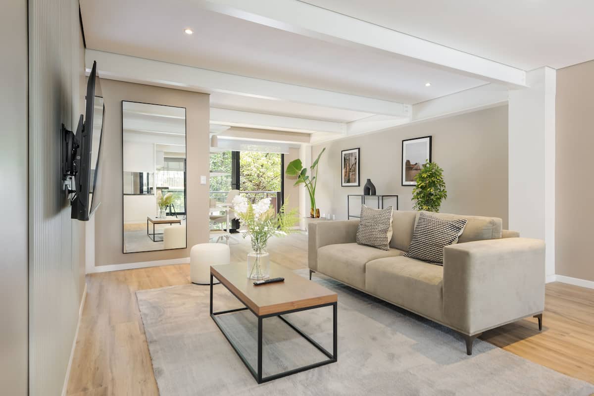 A modern living room with a sofa, coffee table, and a large mirror.