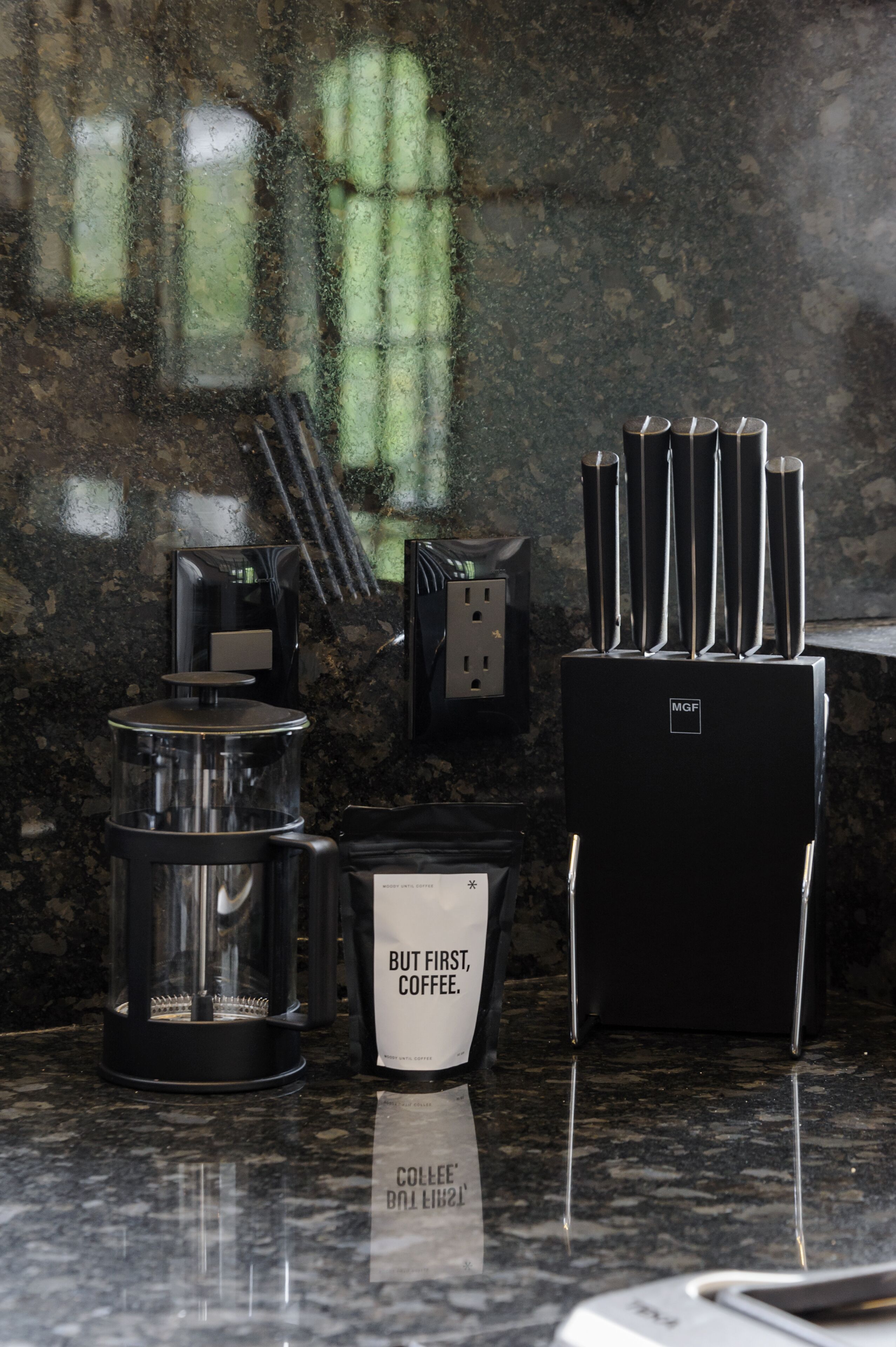 A kitchen counter with a coffee maker, a mug, and a knife block.