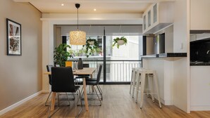 A modern kitchen with white cabinets, a black countertop, and hanging plants. - Wynwood House Nuevo Leon (Mexico City)