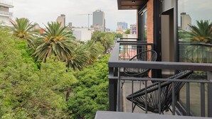 A balcony with a view of the city skyline, lush greenery, and modern architectural design. - Wynwood House Nuevo Leon (Mexico City)