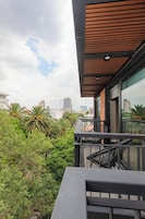 Un balcon offrant une vue sur les gratte-ciel de la ville, une végétation luxuriante et une architecture moderne.