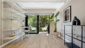 A modern living room with a wooden floor, white shelving units, a black console table, and a large potted plant. - Wynwood House Nuevo Leon (Mexico City)