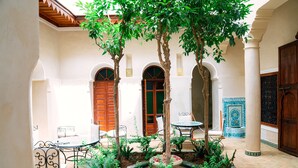 A courtyard with a fountain, seating area, and a door with a blue tile pattern. - Riad Dar Zaouia (Marrakech)