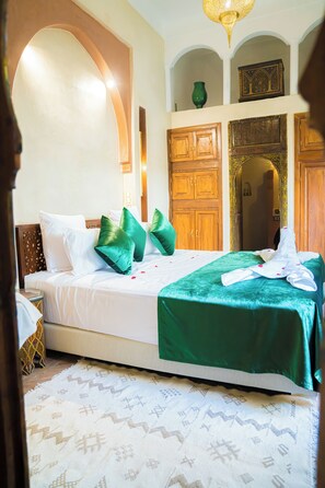 A hotel room with a large bed, green and white bedding, wooden wardrobe, and a patterned rug. - Riad Dar Zaouia (Marrakech)