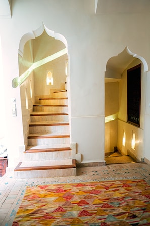 A staircase with a patterned carpet and a wall with a decorative arch. - Riad Dar Zaouia (Marrakech)
