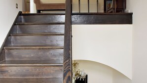 A wooden staircase with a black handrail leading to a landing. A mirror hangs on the wall above the landing, and a bookshelf is visible to the right. - Calm escape in historical athmosphere - Villa Giulietta Budapest,  free parking  (Budapest)