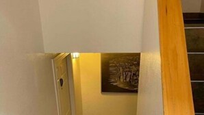 Un escalier avec une rampe en bois, un tapis noir au bas et un tableau accroché au mur.