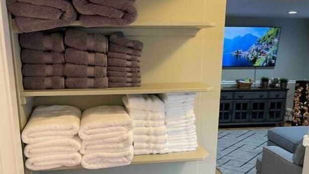 Un espace de rangement bien organisé, doté de plusieurs étagères où sont pliées des serviettes de différentes couleurs.