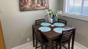Un coin repas avec une table dressée pour quatre personnes, entourée de chaises en bois.