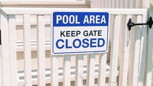Une porte sur laquelle est apposée une pancarte indiquant : « ZONE PISCINE – VEUILLEZ GARDER LA PORTE FERMÉE. »