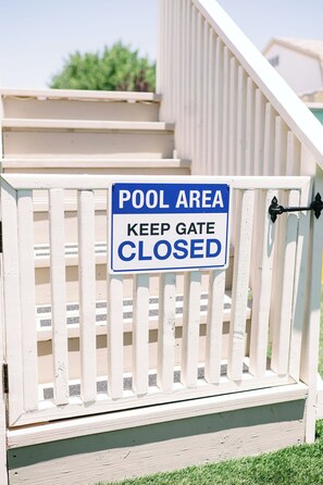 Una cancela con un letrero que dice 'ZONA DE PISCINA MANTENGA LA CANCELA CERRADA'.