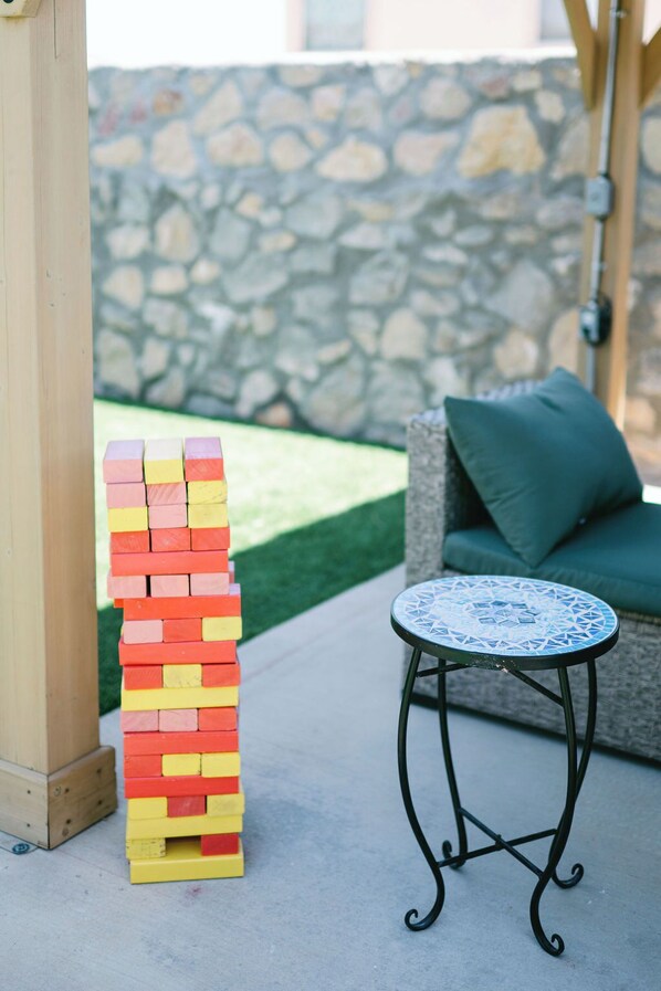 A stack of colorful wooden blocks, a round table with a blue patterned top, and a stone wall in the background.