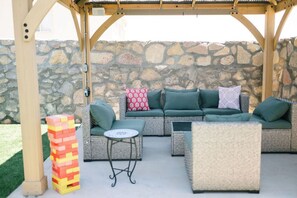 An outdoor seating area with a stone wall backdrop, cushioned seating, and a small table.
