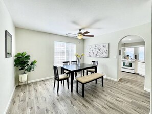 A dining area with a dark wooden table and chairs, a ceiling fan, and a potted plant. - Luxury 4BR Family Home w/ King Suite + Game Room (Chico)