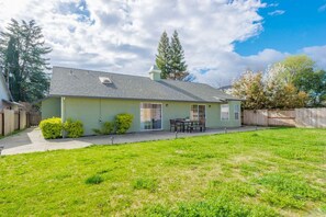 A single-story house with a covered patio area, a fenced backyard, and a clear sky.