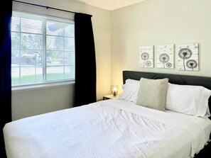 Une chambre d’hôtel avec un lit, une table de chevet, une lampe et des œuvres d’art accrochées au mur.