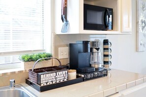A kitchen with a coffee maker, a microwave, and a spatula hanging on the wall. - Luxury 4BR Family Home w/ King Suite + Game Room (Chico)