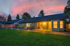 Une maison d’habitation dotée d’un patio couvert, d’une pelouse et offrant une vue sur un ciel dégagé.