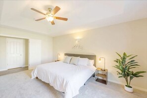 A bedroom with a bed, nightstands, a ceiling fan, a wall-mounted light, and a potted plant. - Luxury 4BR Family Home w/ King Suite + Game Room (Chico)