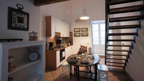 A kitchen with a dining table, wooden cabinets, and a staircase. - Delightful and elegant apartment in the heart of Palermo. (Palermo)