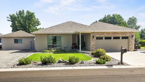Ein eingeschossiges Haus mit Garage, einer Veranda und einem gepflegten Rasen.