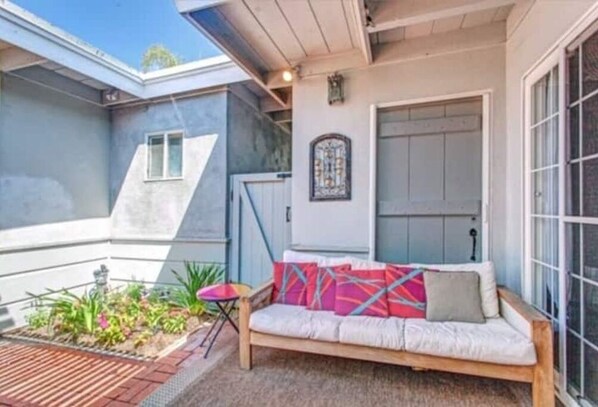 Relax in a tranquil outdoor space with a comfortable bench and small table for dining or enjoying a beverage.