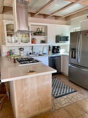 Enjoy cooking in this well-equipped kitchen with a central island, gas stove, and stainless steel refrigerator.