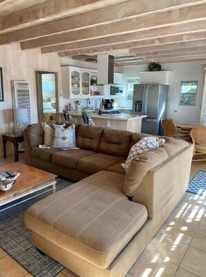 Relax in this spacious living room with a large sofa, dining area, and kitchen.