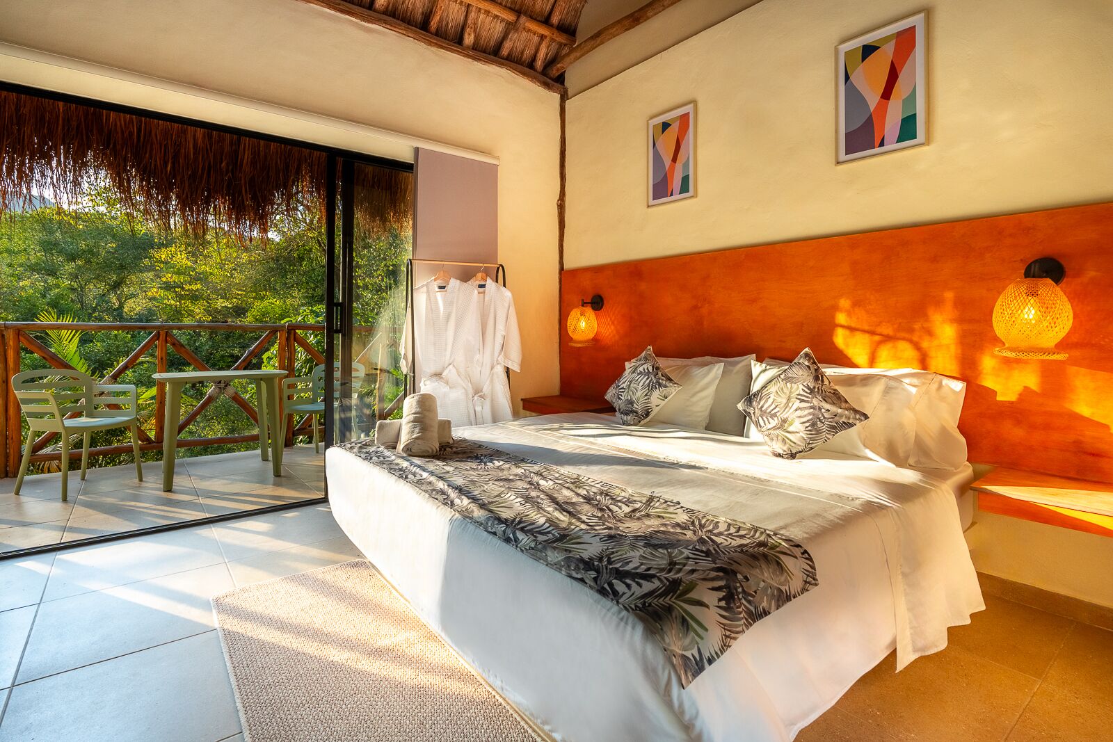 Une chambre avec un grand lit, une tête de lit en bois et une vue sur la verdure.