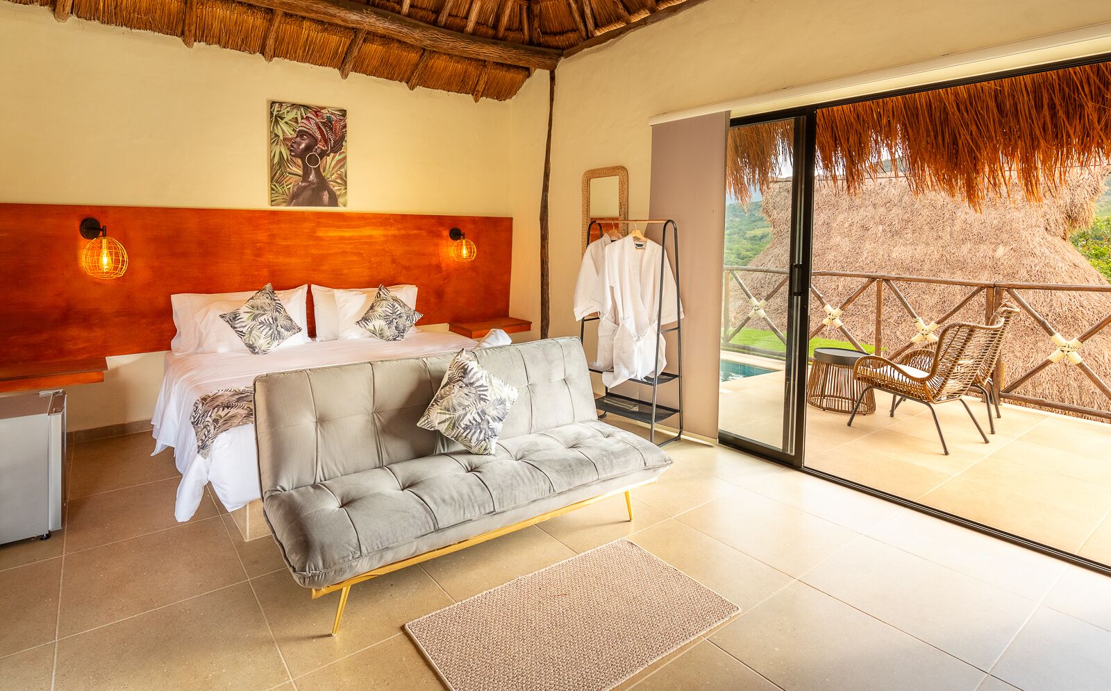 Un dormitorio con cama, sofá, escritorio y vistas a un área exterior con sillas y piscina.