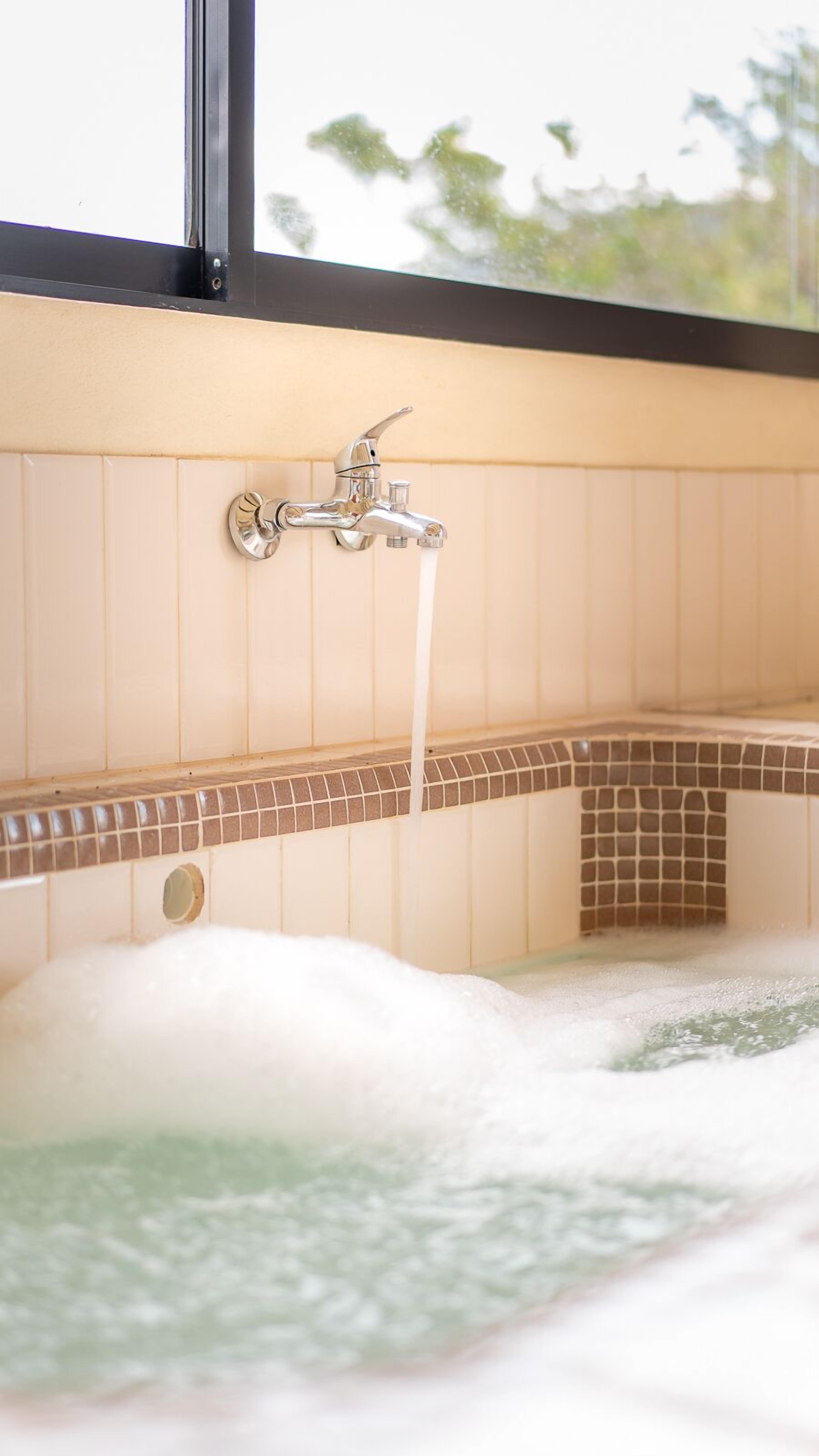 A bathtub with a faucet and a view of the outdoors through a window.