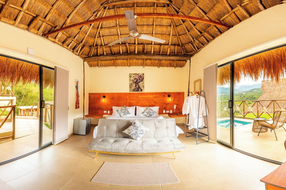 Un dormitorio con una cama grande, ventilador de techo y vistas a una piscina.