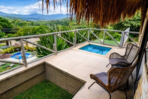 Zona de piscina en la azotea con vistas a montañas, una piscina pequeña y una silla de mimbre.