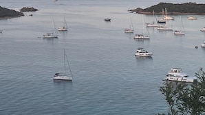 Una marina costera con varios veleros y yates fondeados en aguas tranquilas.