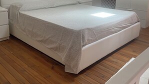 Un dormitorio con cama, suelo de madera, un armario blanco y un tragaluz.