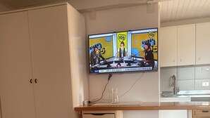 Una cocina con un televisor sobre la encimera, un fregadero y un taburete.