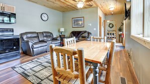 A cozy living room with a wooden ceiling, a dining table, leather sofas, and a kitchen area with appliances. - Cozy Lake Wissota Escape w/ Community Dock! (Chippewa Falls)