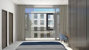 A modern bedroom with a large bed, a chair, and a view of a building through a glass door. - Oscar Villa (Da Nang)