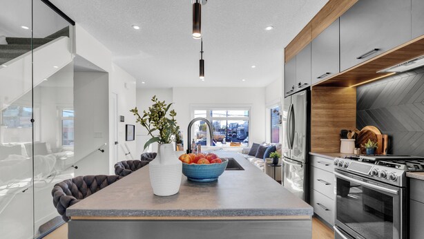 Een moderne keuken met een centraal eiland, roestvrijstalen apparatuur en uitzicht op de woonruimte.